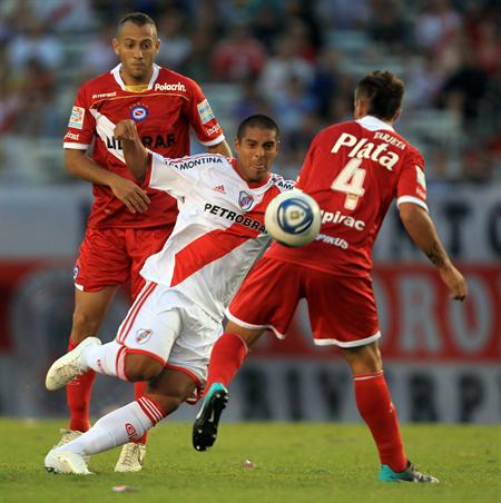 El jugador de River Plate Walter Acevedo (c) disputa el balón con Miguel Torrén (d) y Gonzalo Prósperi (i) de Argentinos. Foto: EFE