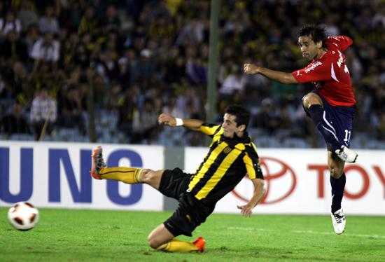 El jugador de Independiente Facundo Parra (d) anota un gol ante la marca de Alejandro González (i) de Peñarol. Foto: EFE