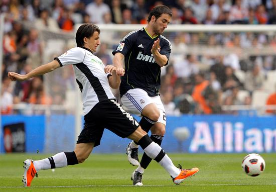 El delantero argentino del Real Madrid Gonzalo Higuaín (d) lucha un balón con el centrocampista turco del Valencia Mehmet Topal. Foto: EFE