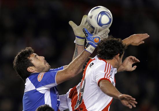 El jugador Adalberto Román (d) River Plate, salta para cabecear el balón ante la marca del portero Diego Pozo (d) de Colón. Foto: EFE