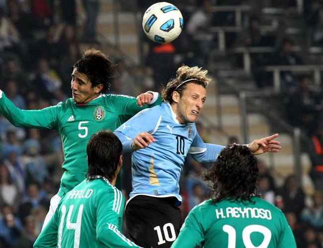 Diego Forlán (arriba, der) disputa el balón con su rival de México Darvin Chávez. Foto: EFE