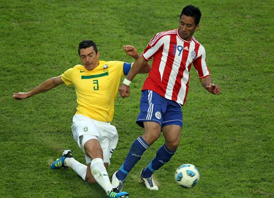 El jugador de la selección de fútbol de Brasil Lúcio (izq) disputa el balón con Lucas Barrios de Paraguay. Foto: EFE