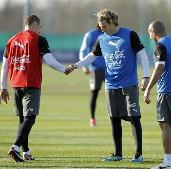 El delantero uruguayo Diego Forlán saluda a su compañero de equipo Diego Pérez (iz) durante la sesión de entrenamiento. Foto: EFE