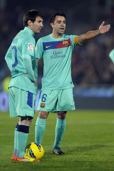 El centrocampista del FC Barcelona, Xavi Hernández (d), y el delantero argentino Lionel Messi (i) se preparan para chutar una falta durante el partido frente al Getafe CF. Foto: EFE