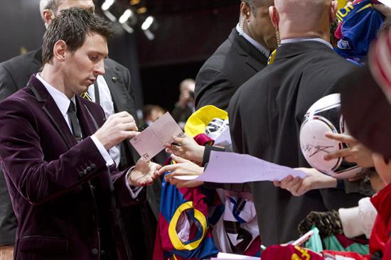 El delantero argentino del FC Barcelona Lionel Messi (i) firma autógrafos en la alfombra roja antes de la gala del Balón de Oro. Foto: EFE
