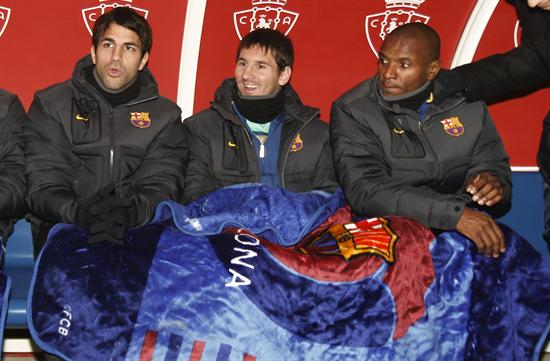 Los jugadores del FC Barcleona, Cesc Fábregas, Leo Messi y Eric Abidal (i-d), se protejen con una manta. Foto: EFE