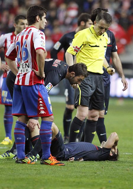 El centrocampista brasileño del Atlético de Madrid Diego Ribas (d) se duele en el suelo tras lesionarse en el Molinón. Foto: EFE