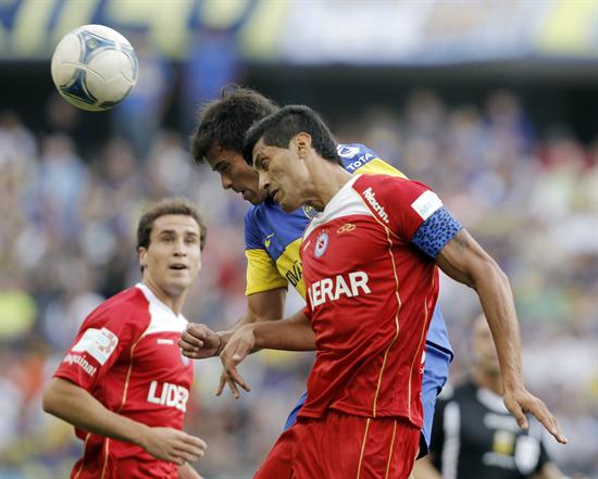 El jugador Darío Cvitanich (c) de Boca Juniors disputa un balón con Sergio Escudero (d) de Argentinos. Foto: EFE