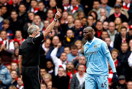 El colegiado Martin Atkinson (i) muestra la cartulina amarilla a Mario Balotelli (d), jugador del Manchester City, durante el partido de la Premier League ante el Arsenal. Foto: EFE