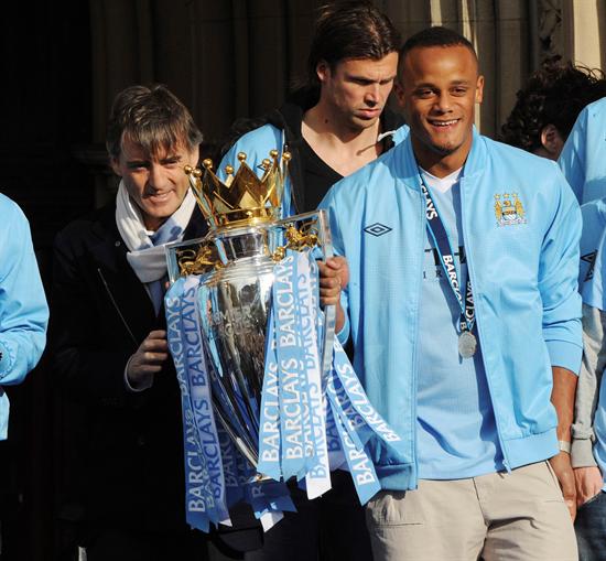 El capitán del Manchester City, Vincent Kompany (dcha), y el entrenador Roberto Mancini (izda), posan con el trofeo de campeones de la Premier League. Foto: EFE