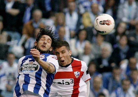 El defensa argentino del Deportivo de La Coruña Diego Colotto (i) cabecea un balón ante el delantero del SD Huesca Roberto García. Foto: EFE