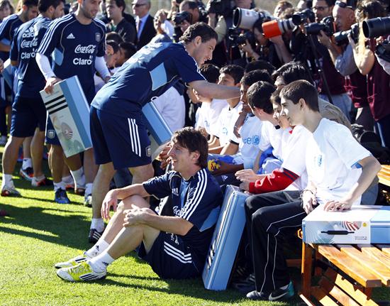 Los jugadores Lionel Messi (c) y Maximiliano Rodríguez (c-i) posan con un grupo de niños. Foto: EFE