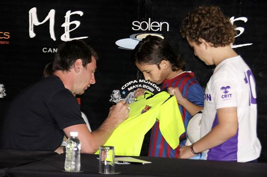 Leo Messi (i) firma un autógrafo a unos niños en Cancún. Foto: EFE