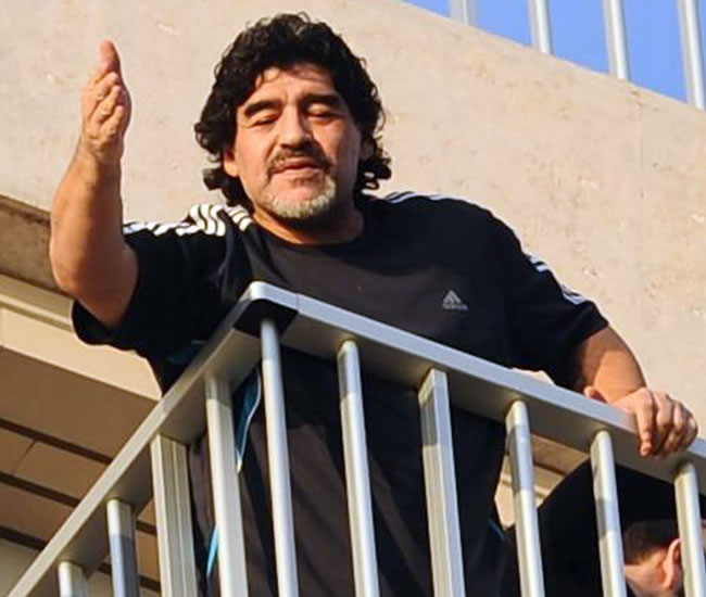 El exfutbolista argentino Diego Armando Maradona saluda a sus seguidores desde el balcón de su hotel en Nápoles. Foto: EFE