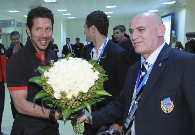 El DT argentino del Atlético de Madrid Diego Simeone (i) recibe un ramo de flores por el día de su cumpleaños a la llegada del club rojiblanco al aeropuerto de Bakú. Foto: EFE