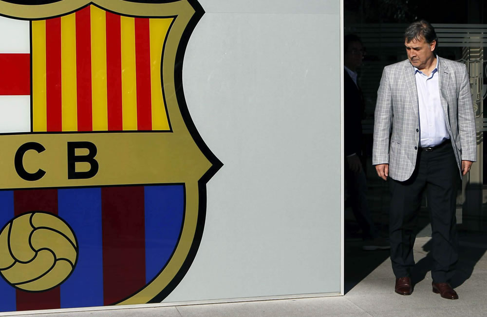 El nuevo DT del FC Barcelona, el argentino Gerardo 'Tata' Martino, posa ante el escudo del club. Foto: EFE