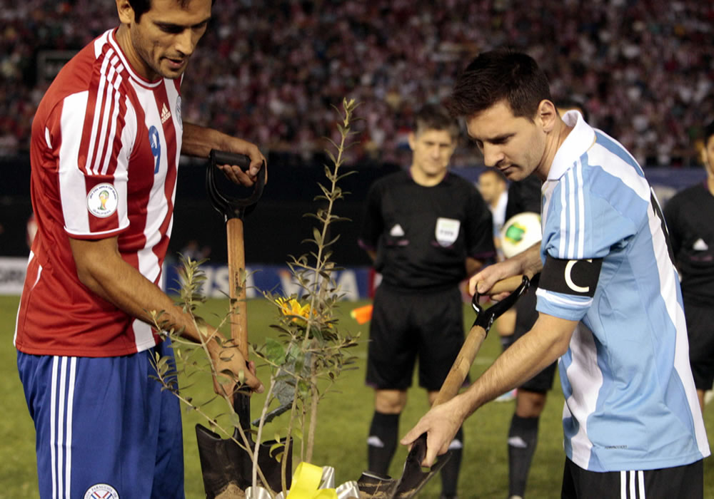 Roque Santa Cruz (i) de Paraguay y Lionel Messi (d) de Argentina ponen arena en una planta de olivo. Foto: EFE