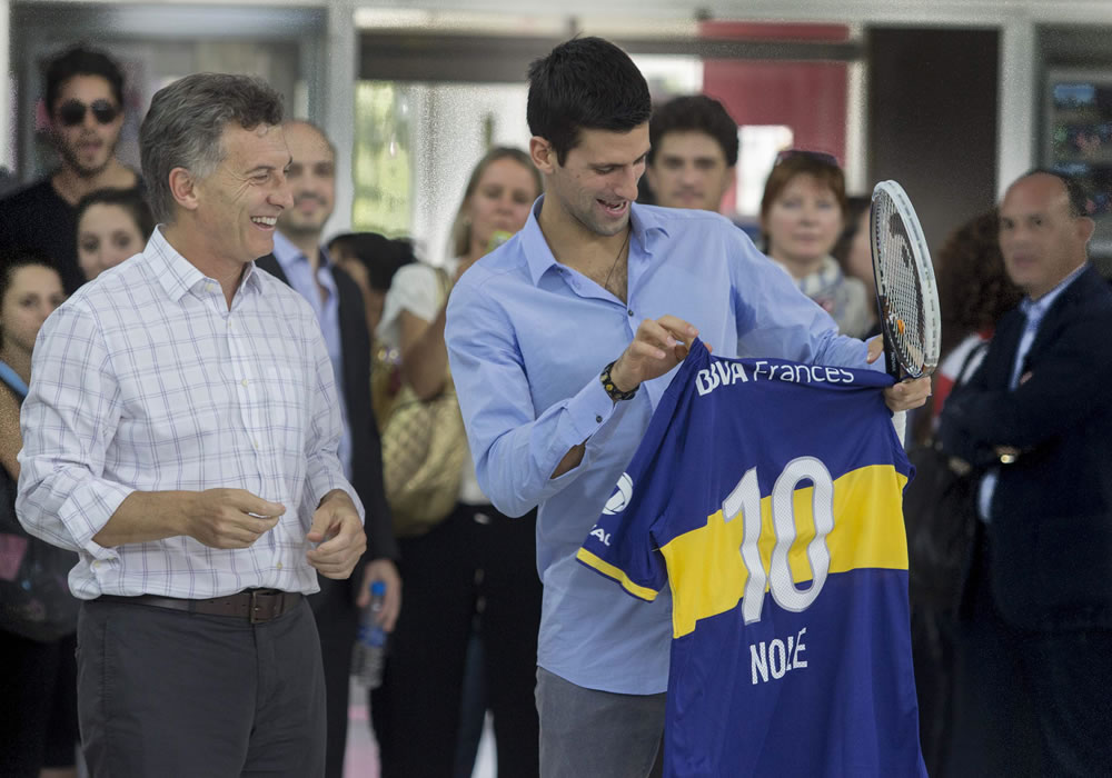 El tenista serbio Novak Djokovic (d) recibiendo una camiseta del club Boca Juniors junto al alcalde de la capital argentina, Mauricio Macri (i), durante un acto en una villa de Buenos Aires. Foto: EFE