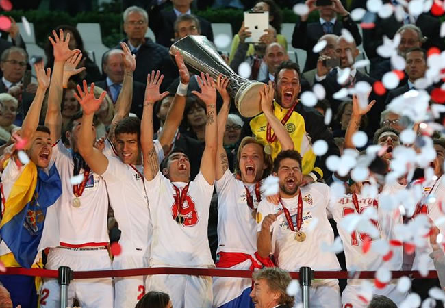 El capitán del Sevilla, Ivan Rakitic (c), sostiene el trofeo de campeones durante la celebración por la victoria ante el Benfica. Foto: EFE