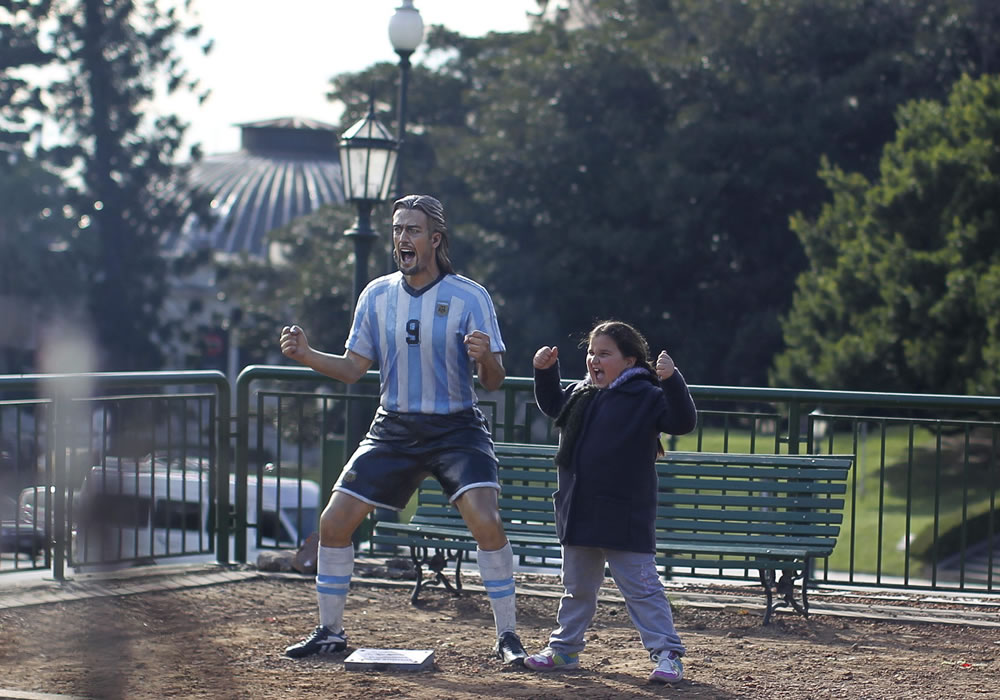 Una niña posa para una fotografía con la escultura del exjugador de la selección argentina Gabriel Batistuta. Foto: EFE
