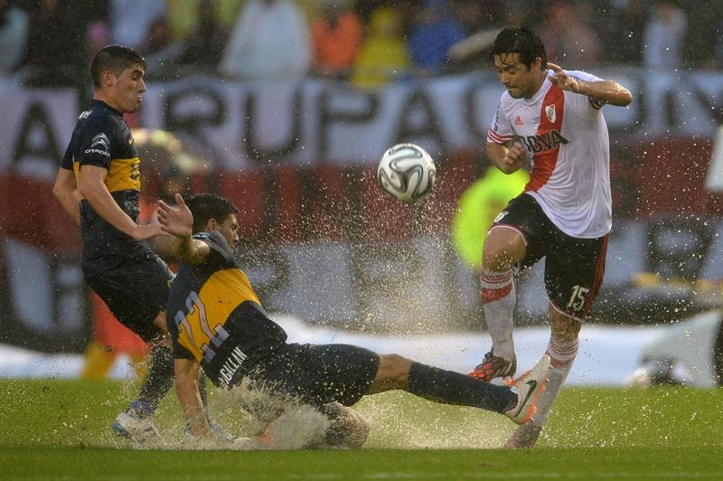 Leonardo Pisculichi (d) del River Plate disputa el balón con Lisandro Magallán (c) de Boca Juniors. Foto: EFE
