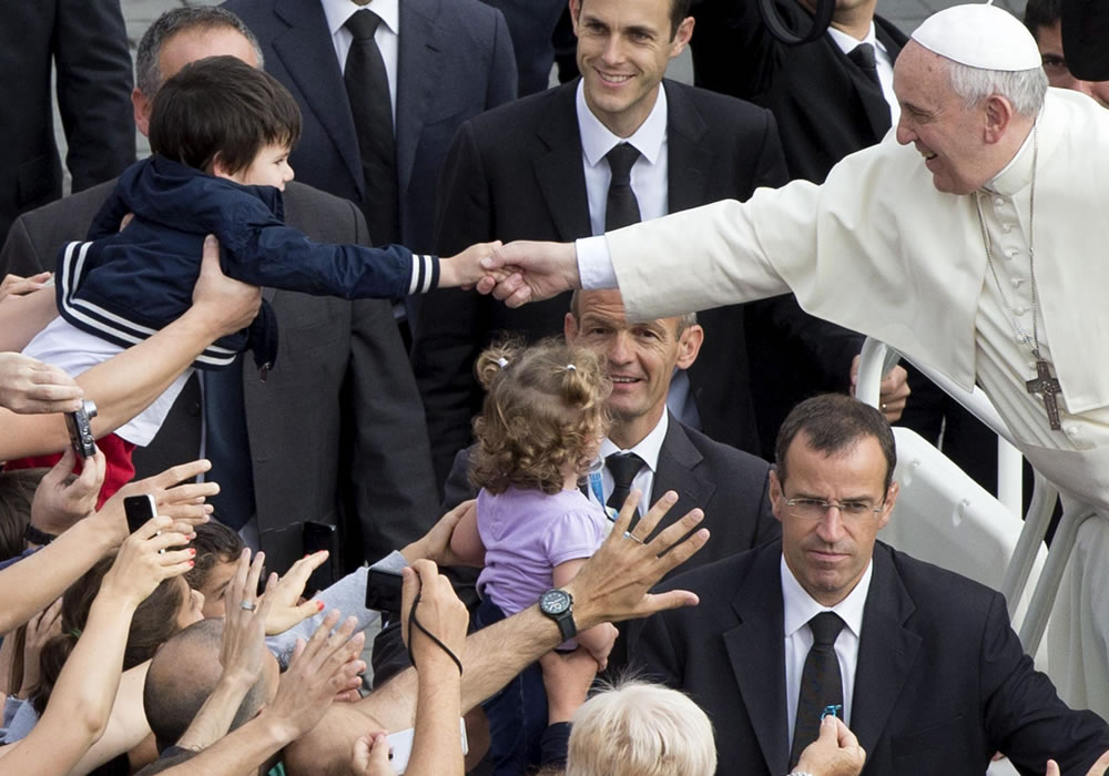 El papa Francisco (dcha) estrecha la mano a un niño a su llegada a la Plaza de San Pedro del Vaticano. Foto: EFE