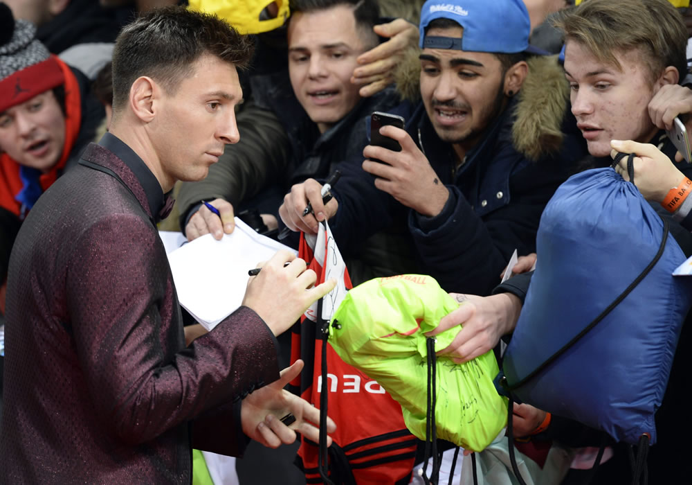 El jugador argentino Lionel Messi (i) firma autógrafos a su llegada a la gala del balón de oro de la FIFA 2014. Foto: EFE