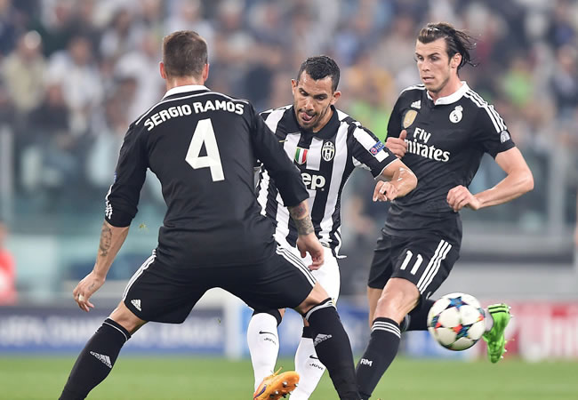 El argentino de Juventus Carlos Tevez (c) patea el balón ante la marca de Sergio Ramos (i) y Gareth Bale (d), de Real Madrid. Foto: EFE